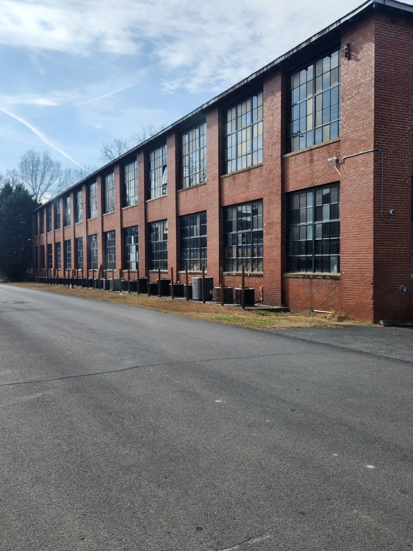 Long brick Mill Town building viewed along the paved drive