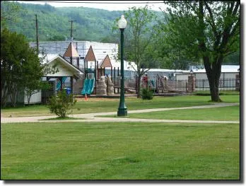 Green community lawn with trees, a path, and a small play area