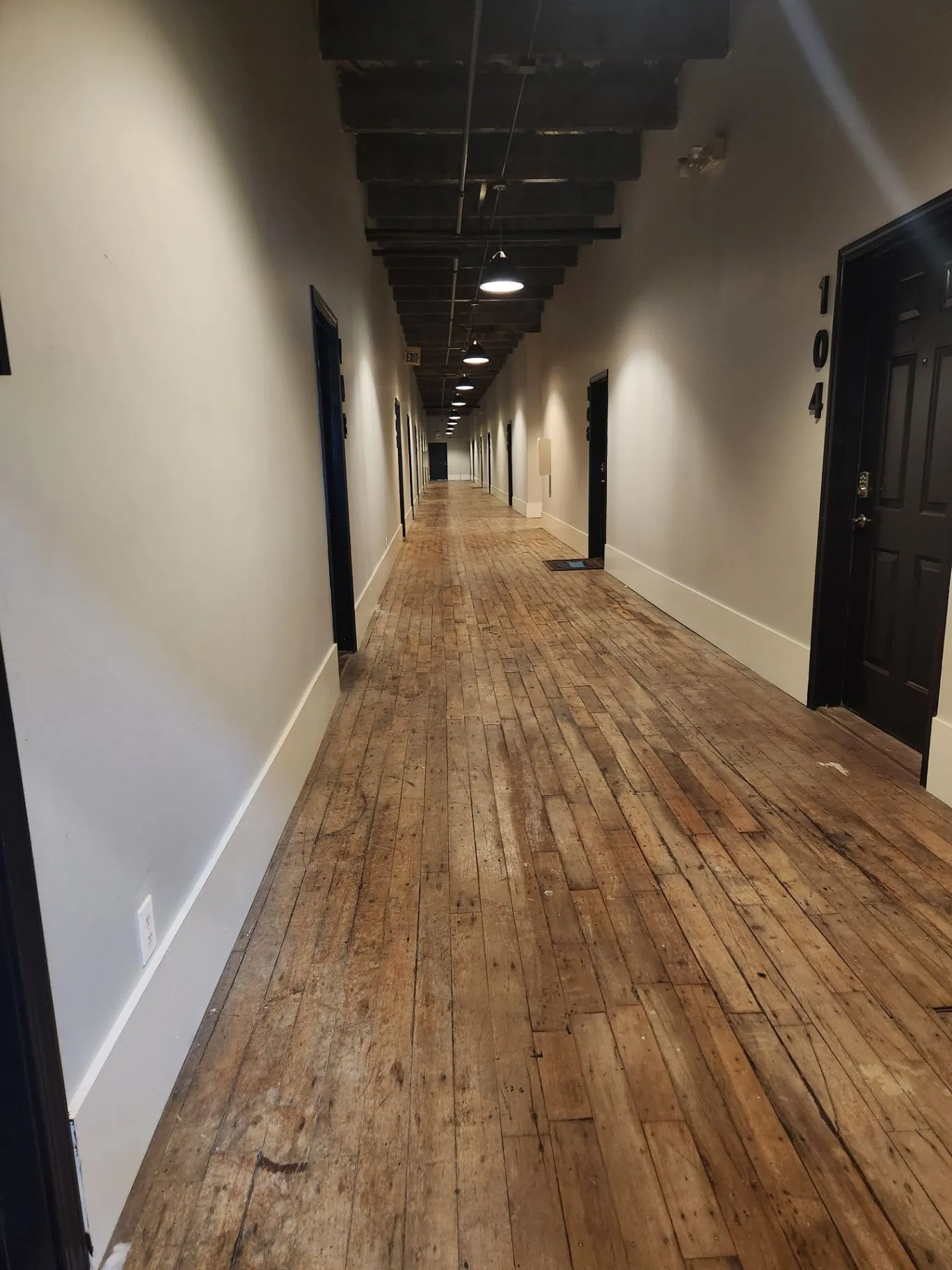 Mill Town interior corridor with wood flooring, dark doors, and exposed beams